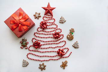 Creative idea for Christmas or New Year theme. A Christmas tree made of beads and a star on top. Next to him lies a gift and traditional gingerbread. Celebratory concept.
