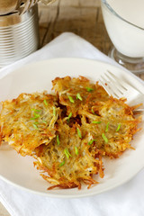 Potato pancakes served with sour cream and green onions on a wooden background. Rustic style.