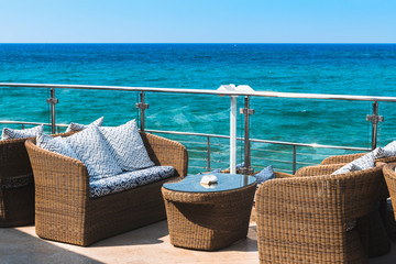View on an empty luxury balcony near the sea with rattan furniture.