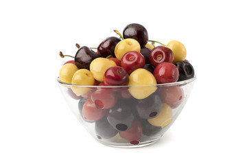 Full glass plate of colored cherries on a white, isolated.
