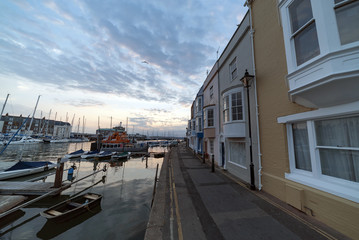 Sunrise at Weymouth Harbour on a warm summer's morning. Boats and small fishing vessels are moored up.