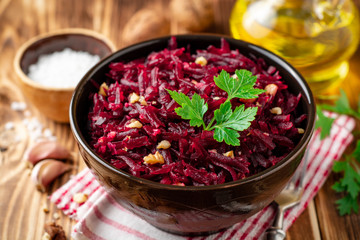 Beetroot salad with wallnuts and garlic in bowl on wooden table