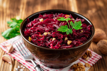 Beetroot salad with wallnuts and garlic in bowl on wooden table