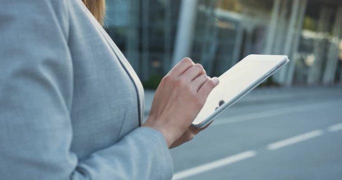 Close up of the female hands in the official jacket taping on the tablet device outside.