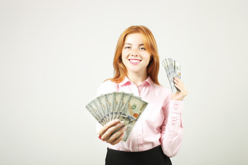 Portrait of young beautiful redhead woman with fistful of money holding one hundred dollar bill stack like fan. Excited attractive red hair female w/ lots of cash. Background, copy space, close up.