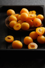 Sweet summer yellow plums on wooden tray. Side view