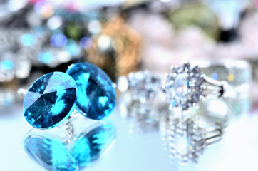 Close-up of blue earrings jewels - reflection effect - colored backgrounds with silver ring