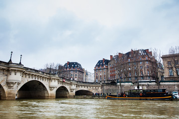 Obraz premium Boat at the Seine river next to the Pont Neuf in a cold winter day in Paris