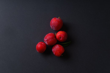 Red sweet cherry plums on dark background. Overhead view