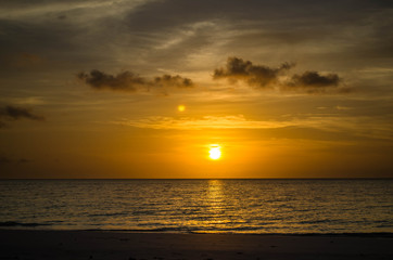 Beautiful golden sunset. The sun is going down behind the horizon of the ocean. Tropical sunset