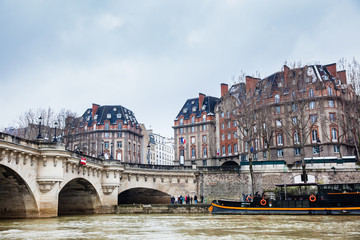 Obraz premium Boat at the Seine river next to the Pont Neuf in a cold winter day in Paris