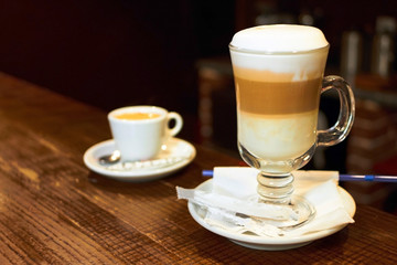 
Latte macchiato and an espresso cup on a wooden bar counter