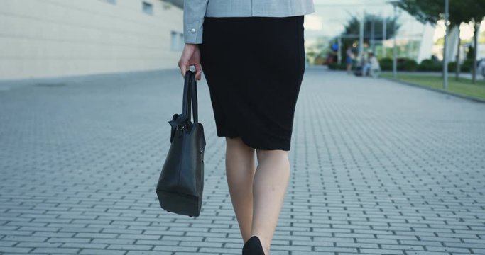 Close up of the Caucasian female feet in black shoes with heels stepping on the street, then camera moving up.