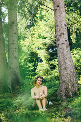 happy innocent woman sitting in green atmospheric forest on background of  mountains in summer