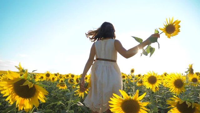 Happy little girl runs happy free across the field with sunflowers. slow motion video. smelling big sunflower on summer field. Delight of a pleasant smell. Summer holiday. concept happiness childhood