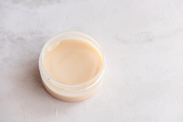 Spa cosmetics, open jar with skin care product on white marble background from above. Beauty blogging concept. Copyspace