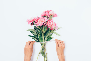 Female's hands decorate a bouquet of pink peony flowers