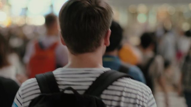 Following Shot of the Traveling Man with a Backpack Walking Through the Crowd of People in the Big City. Young Tourist Travilng or Boy Going to School.