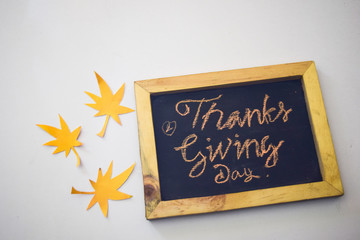 The word Thanksgiving written by hand on a blackboard in white/grey background