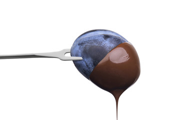 Fondue plum in hot chocolate isolated on white background