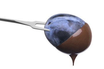 Fondue plum in hot chocolate isolated on white background