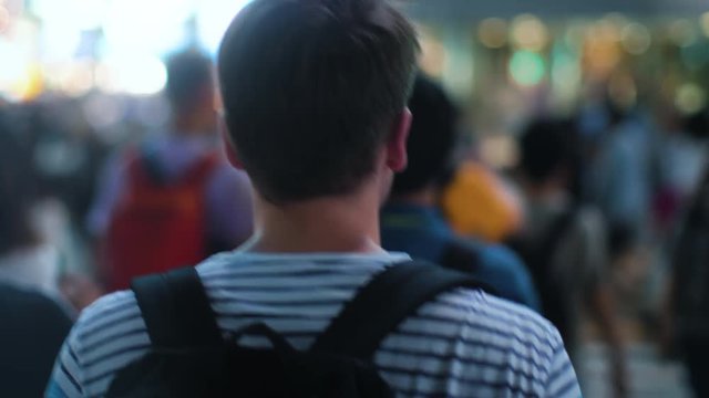 Following Shot of the Traveling Man with a Backpack Walking Through the Crowd of People in the Big City. Young Tourist Travilng or Boy Going to School.