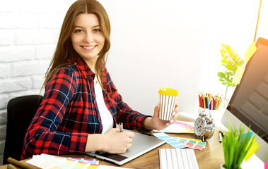 Beautiful young designers discussing ideas and smiling while working in office