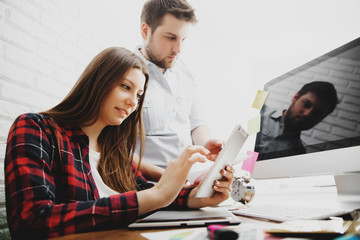 Beautiful young designers discussing ideas and smiling while working in office