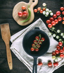 cast iron round frying pan and ripe red cherry tomatoes