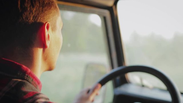 This is close up type portrait footage of young car driver driving jeep during sunset. You can see golden hour light on his face.