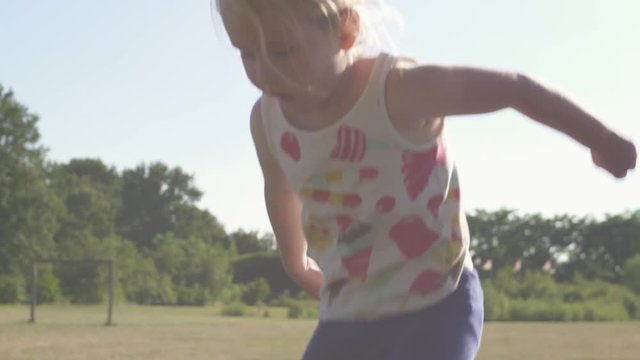 Cute 3 year old child, girl jumping on a trampoline. Slow motion. Medium close. Sunflare, campside and Realistic.