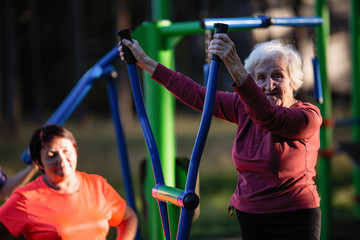 Obraz premium Elderly woman is doing exercises on the sport playground in the Park.