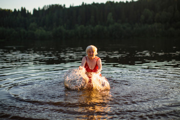 Elderly woman swimming in the river at sunset.