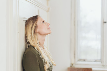 Young woman standing daydreaming indoors