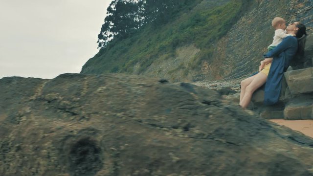 4 k beautifull young girl, mother walking and taking time with her cute little baby, among the Cantabrian coast, in the bay of Atlantic ocean at cloudy morning