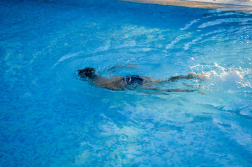 Defocused blurry underwater swimmer, recreational relax in swimming pool sunny outdoors background. Unfocused blurred person having fun on vacation holiday.