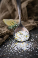 Lemon Lavender Herb Salt in Tarnished Spoon on Black Background with Fresh Sprig of Lavender