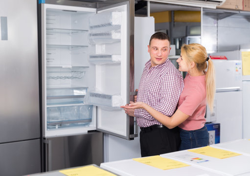 Positive family couple choosing new  refrigerator in store