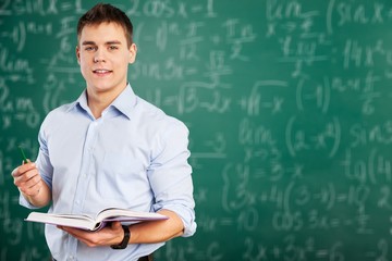 Young teacher near chalkboard in school classroom