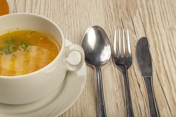 Plate with soup and cutlery on a wooden background.