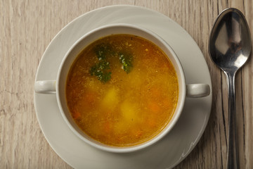 Plate with soup and cutlery on a wooden background.