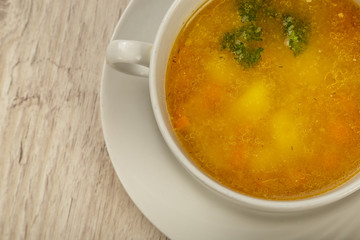 Plate with soup in a white plate on a wooden background.