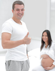 Obraz premium portrait of the future father showing thumb up while standing in a new apartment