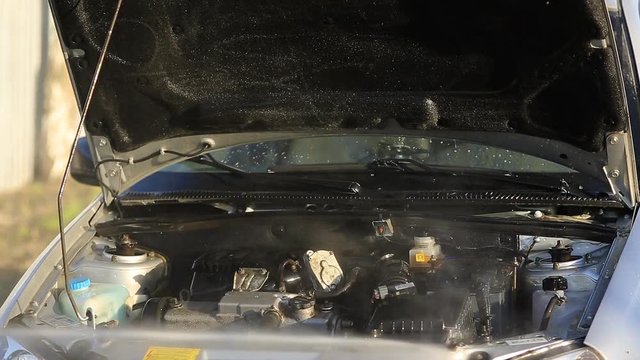 Young attractive man perfusing with water his silver car