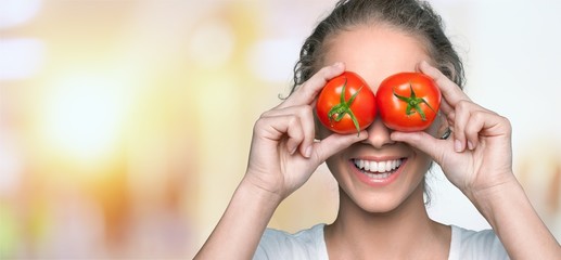Beautiful laughing woman holding two ripe tomatoes
