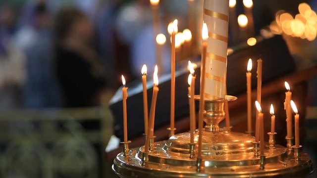 Burning candles in front of the altar in the church. Praying parishioner of the church.