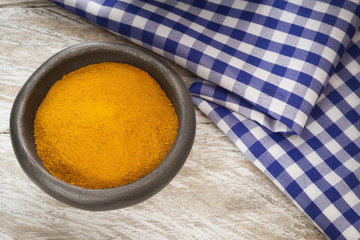 Ground turmeric in a bowl on wooden background- turmeric longa