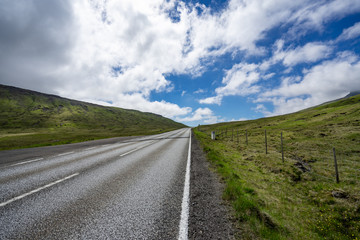 Fototapeta na wymiar Empty asphalt road on the the mountain through blue sky with clouds, no ending unknown future ahead or hope for brightness or adventure travel