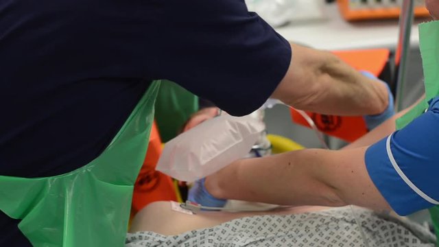 Close-up of nurses’s hands. Training on real person, learning how to use an artificial respiration apparat, holding head straight.
