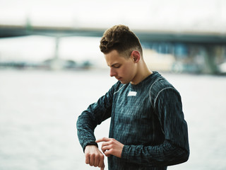 Profile view of teenage boy checking tracking wristband on his hand after running practice